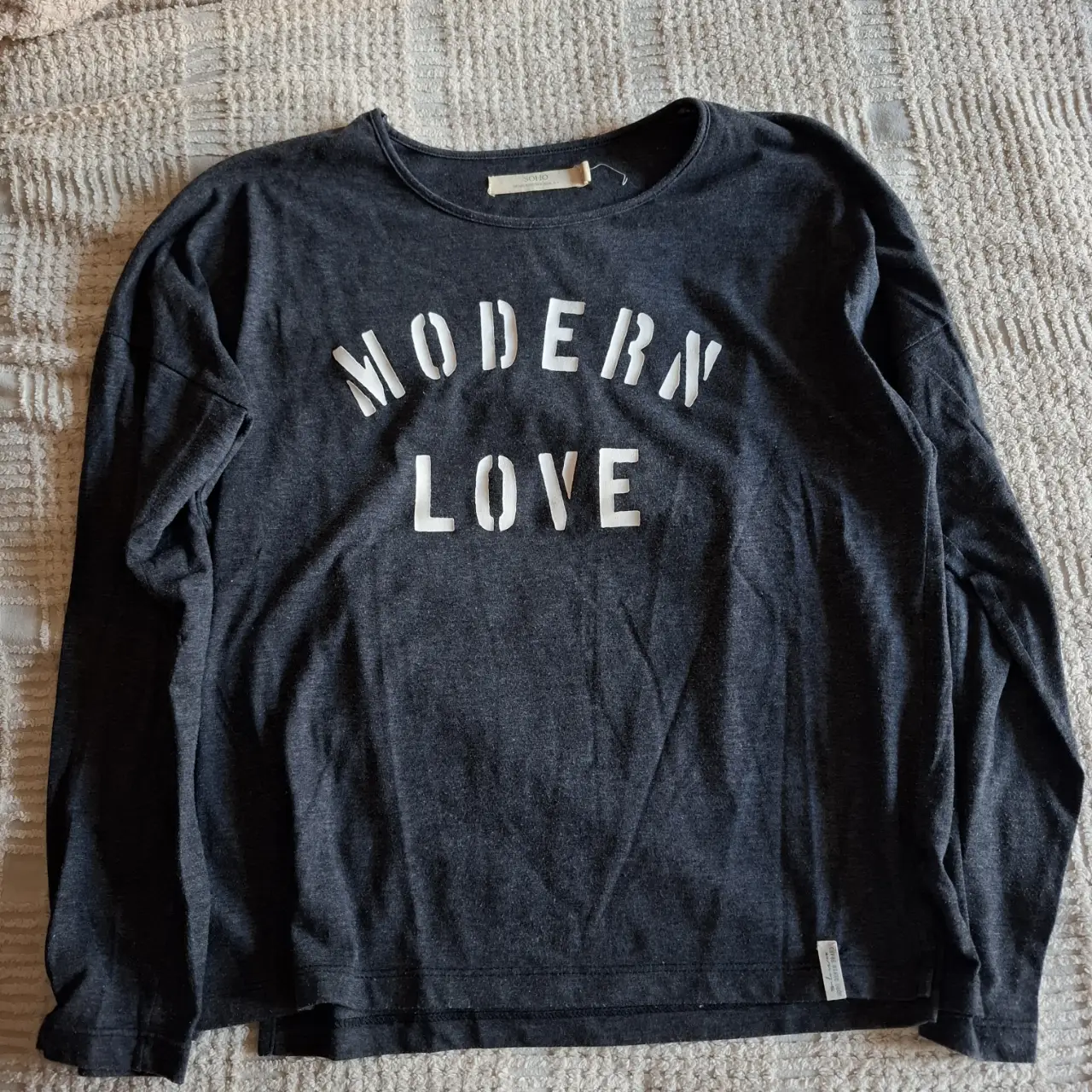Remera de manga larga para mujer, color gris con estampado "MODERN LOVE" en blanco. Ideal para un look casual y moderno.