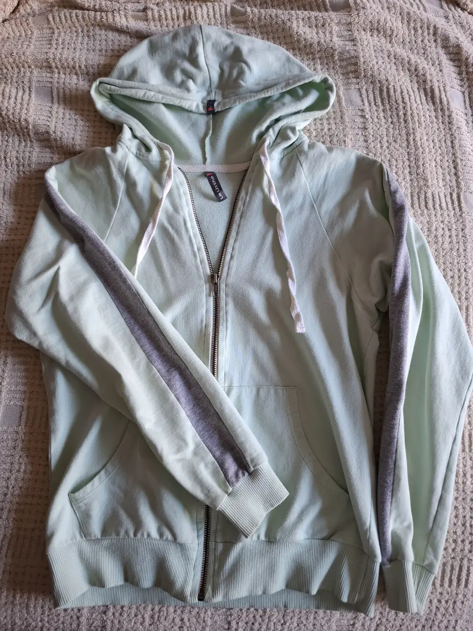 Buzo con cierre y capucha para mujer, de color verde agua con detalles grises en las mangas. Talle S. Ideal para un look casual y cómodo.