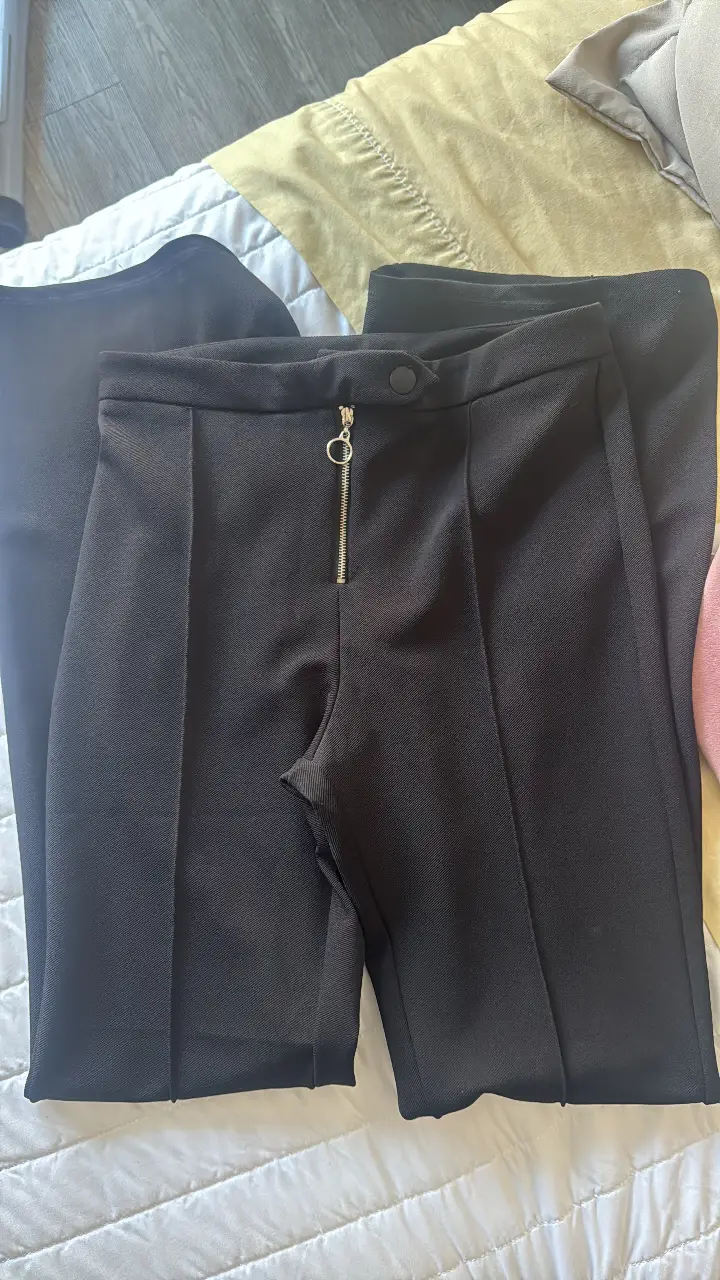 Pantalón sastrero negro con cierre y botón en la cintura. Diseño elegante y versátil, ideal para looks formales o casuales.