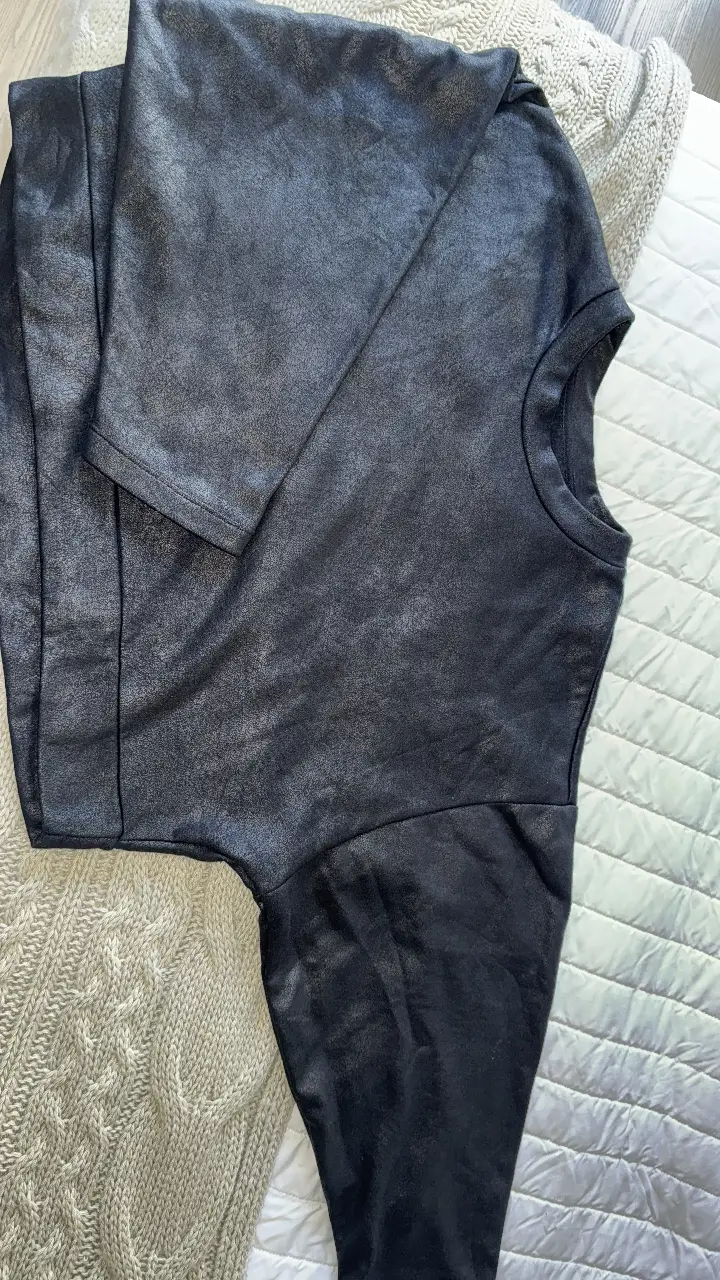 buzo oversize negro con mangas murciélago, ideal para un look elegante y versátil. Confeccionado en un material con brillo sutil, perfecto para ocasiones especiales o salidas.