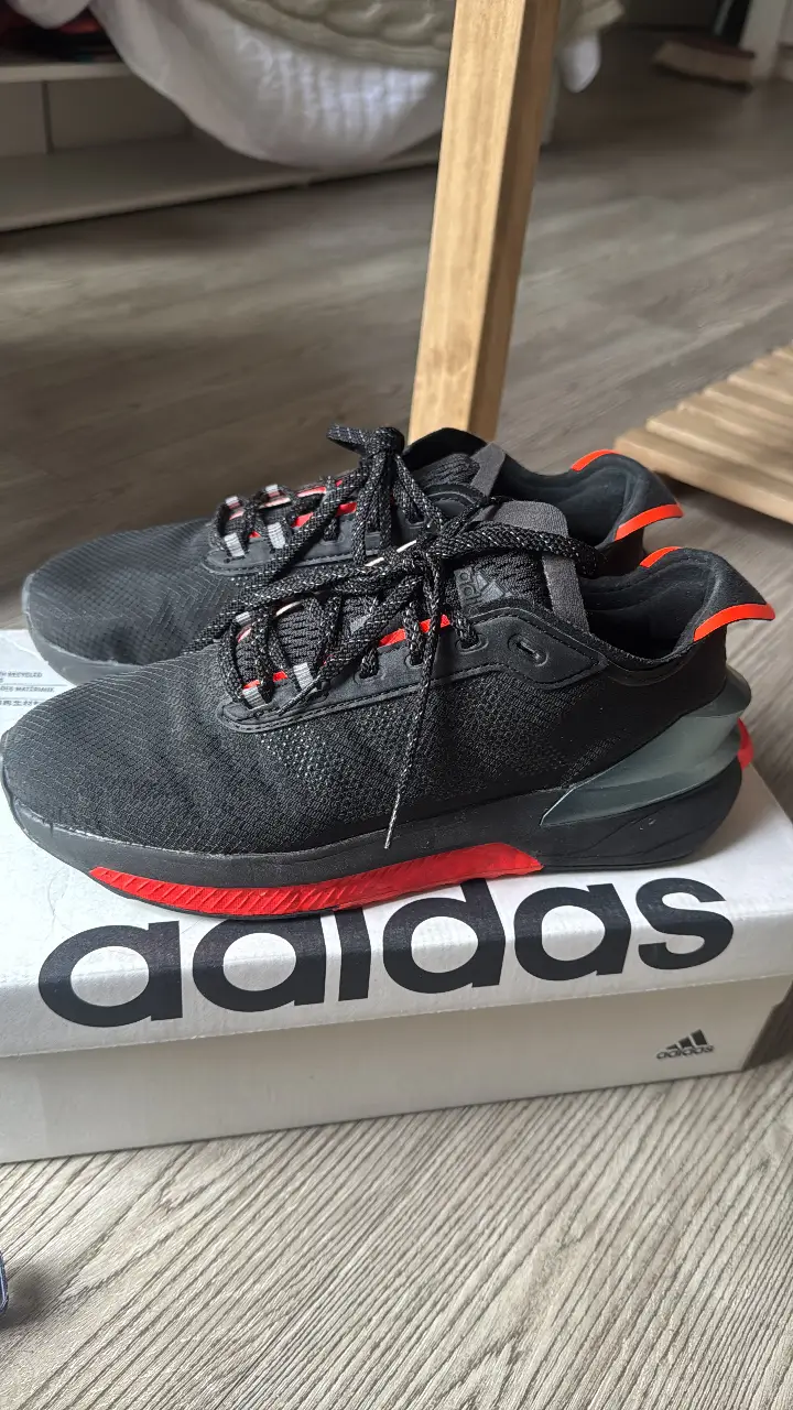 Zapatillas Adidas negras con detalles en rojo, ideales para running y uso diario. Diseño moderno y cómodo.