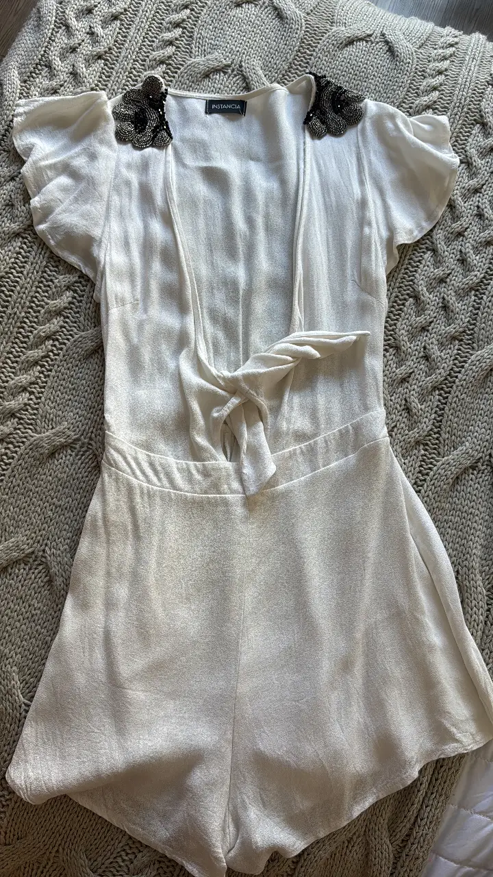 Mono corto blanco con detalles de lentejuelas en los hombros. Ideal para un look de fiesta o salida.