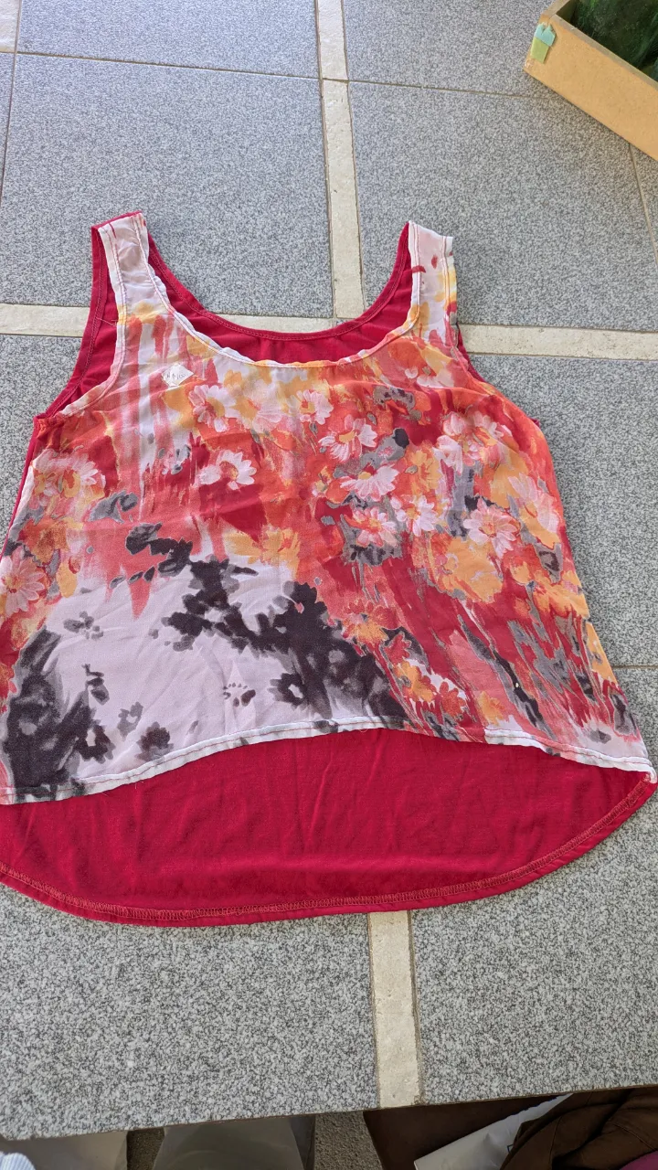Musculosa con estampa floral en tonos rojos, naranjas y blancos. Base lisa en color rojo.