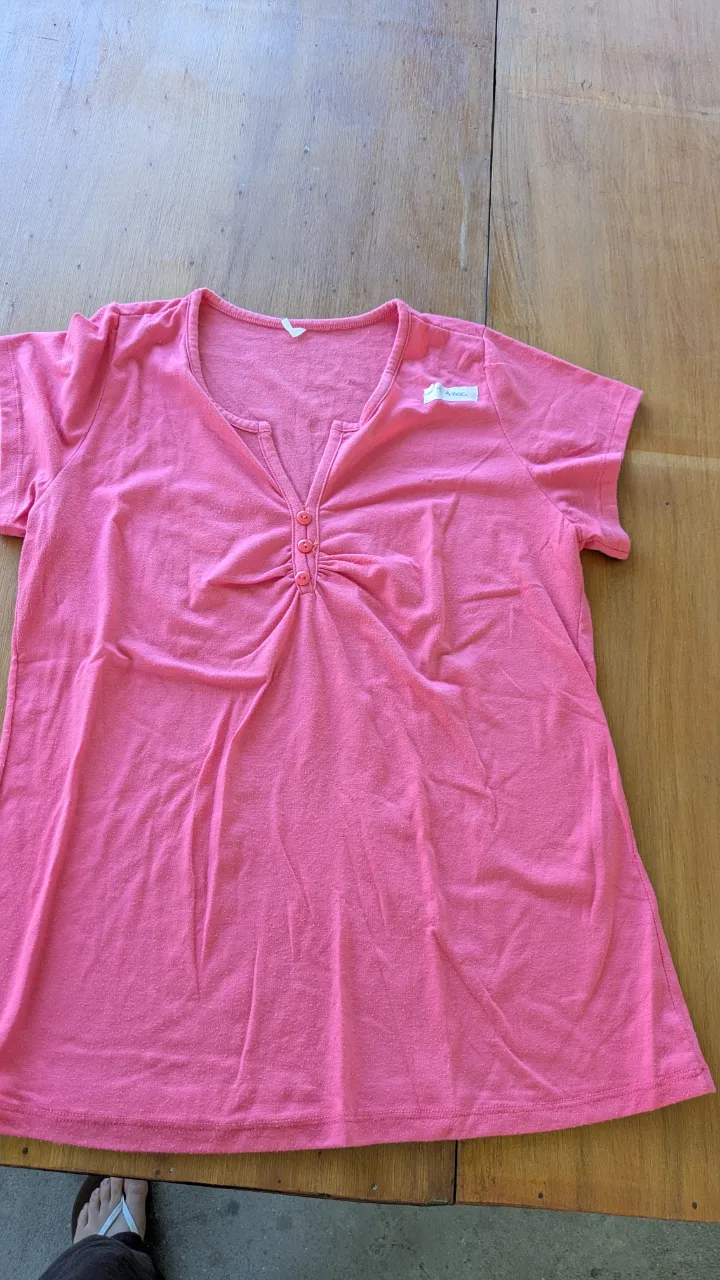 Remera manga corta de color rosa vibrante, con escote en V y detalle de botones en la parte superior. Perfecta para un look casual y cómodo.