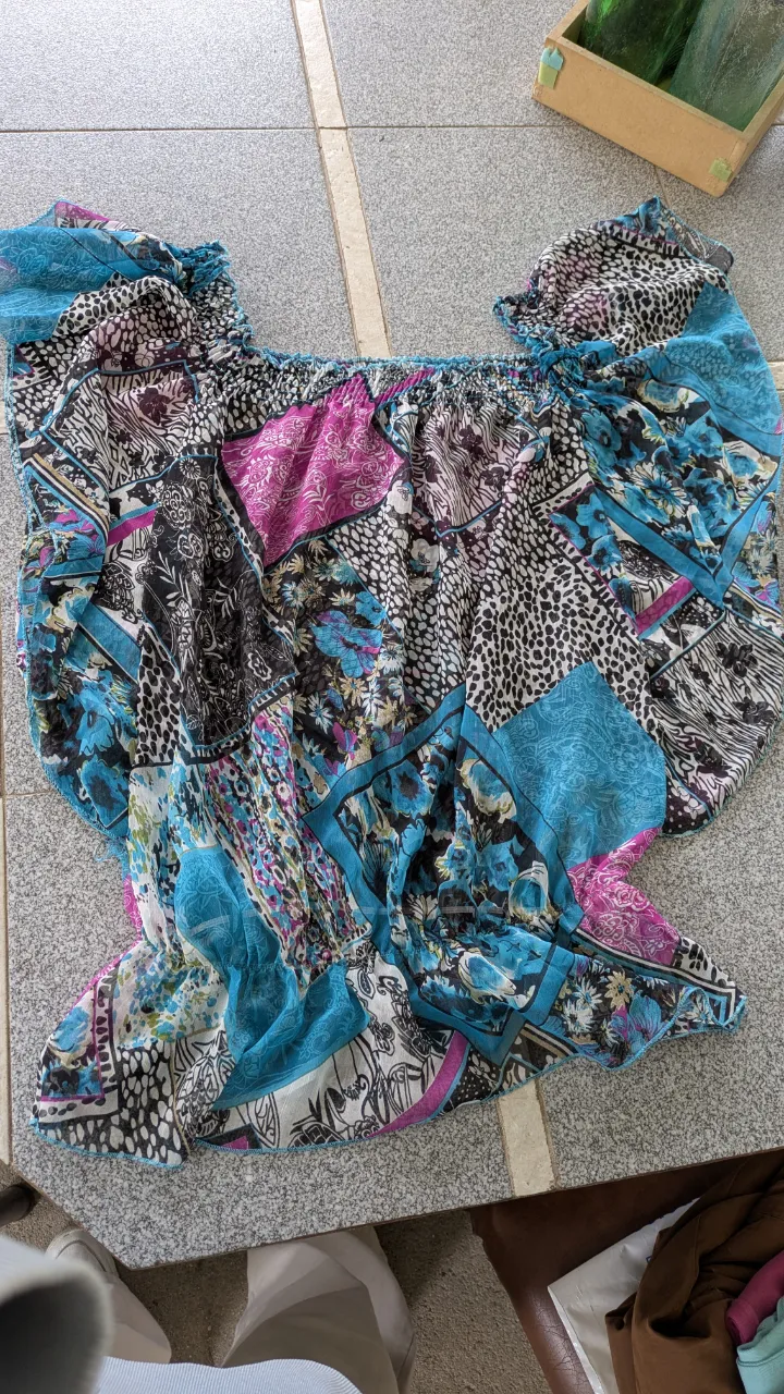 Blusa estampada con múltiples diseños y colores vibrantes. Posee cuello elástico y mangas cortas con volados.