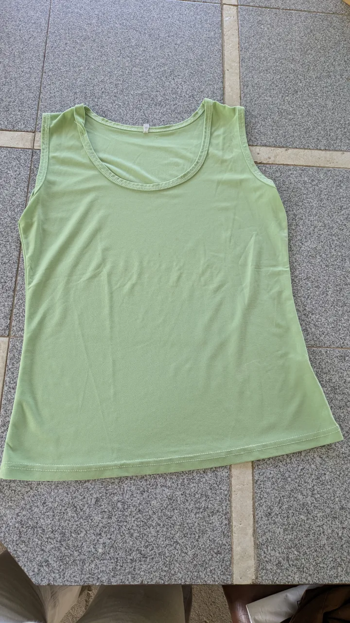 Musculosa de color verde claro con cuello redondo. descocida en un costado