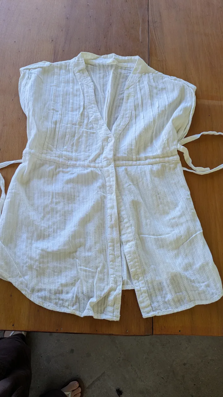 Blusa blanca de algodón con detalles de bordado y lazo para atar en la cintura. Ideal para un look fresco y casual.