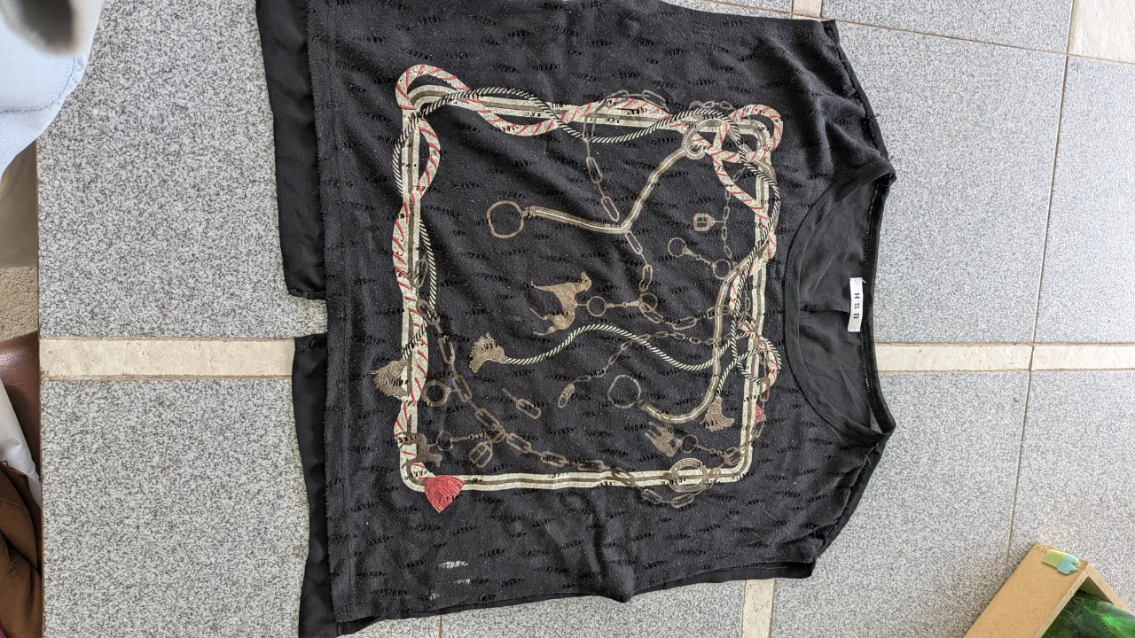 Remera negra con estampa de cadenas y detalles en el frente. Posee un recorte en la espalda con tela de encaje.