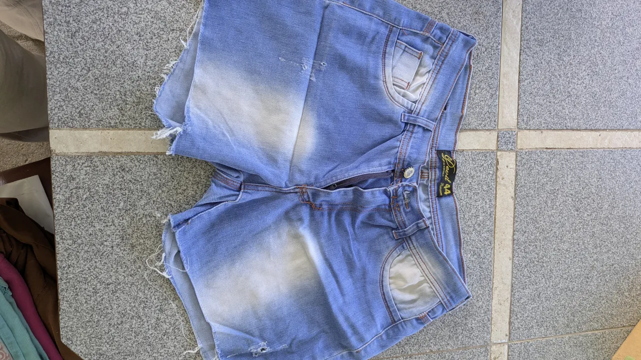 Shorts de jean tiro alto, con roturas y deshilachados en los bordes. Presenta desgaste de color en la parte delantera y trasera.