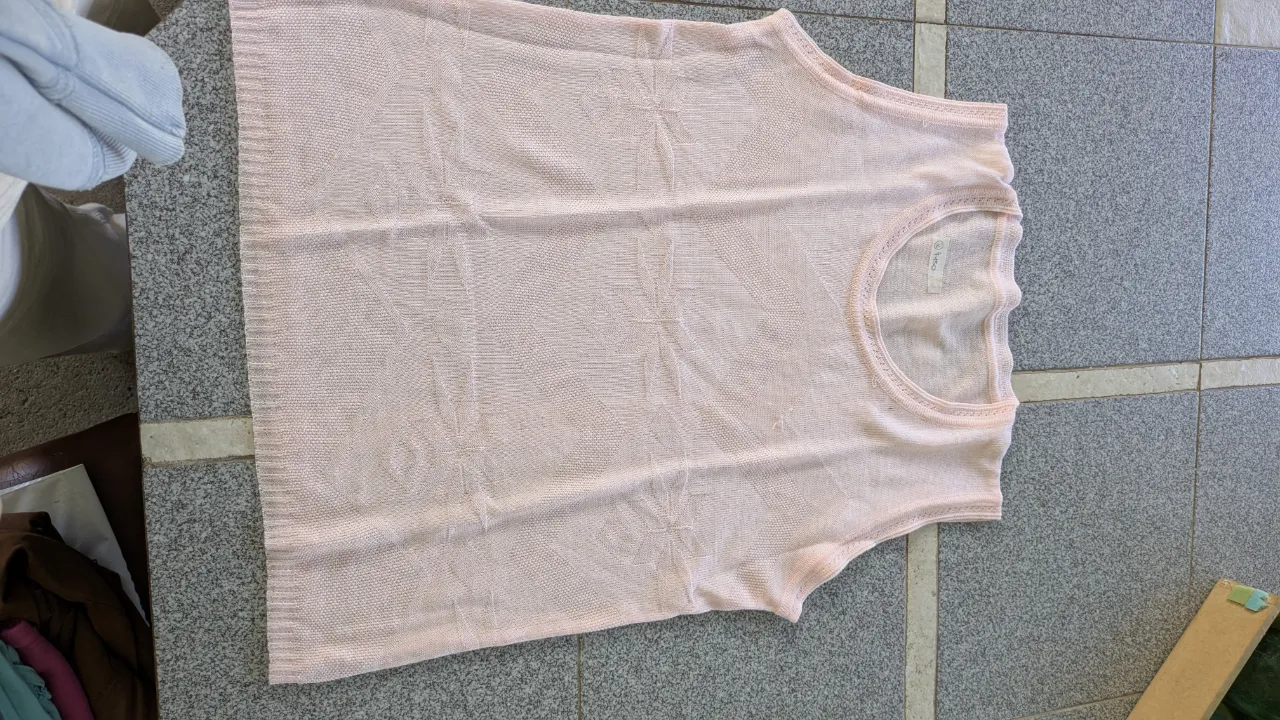 Musculosa de tejido liviano color rosa pálido con detalles texturados.