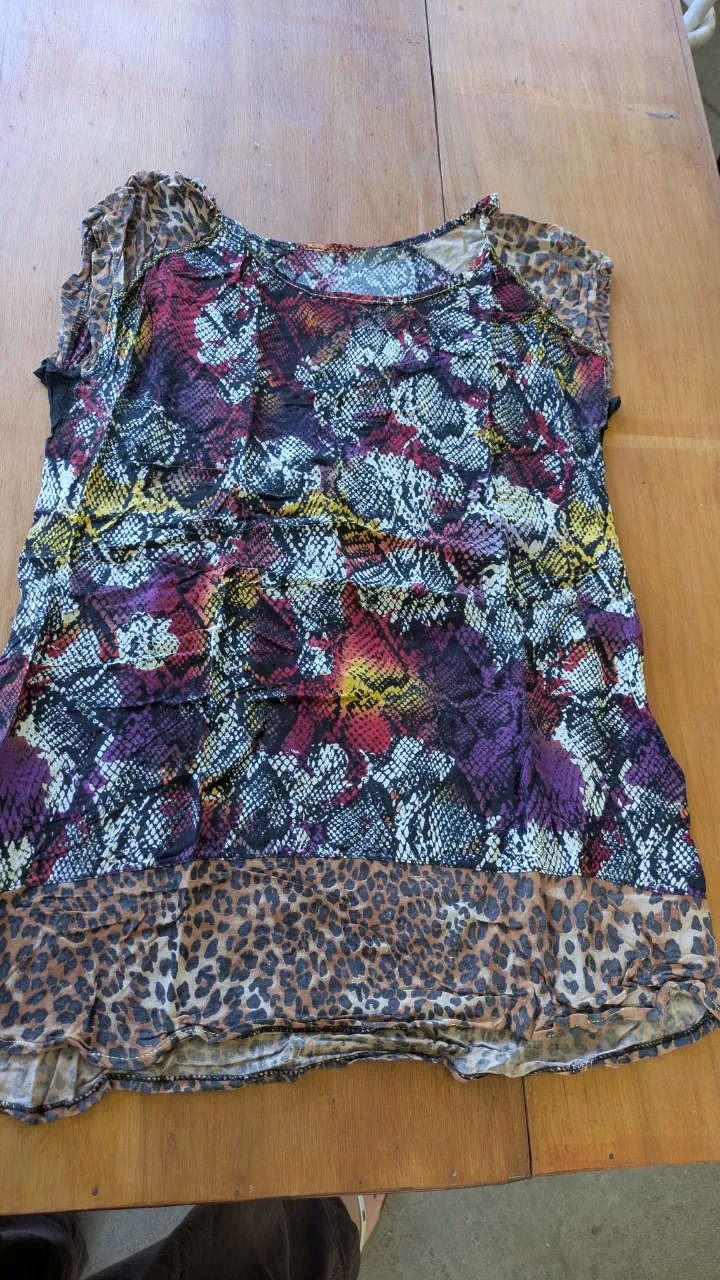 Remera estampada con diseño de serpiente y detalles de leopardo. Posee mangas cortas con terminación desflecada y cuello redondo. Ideal para un look audaz y moderno.