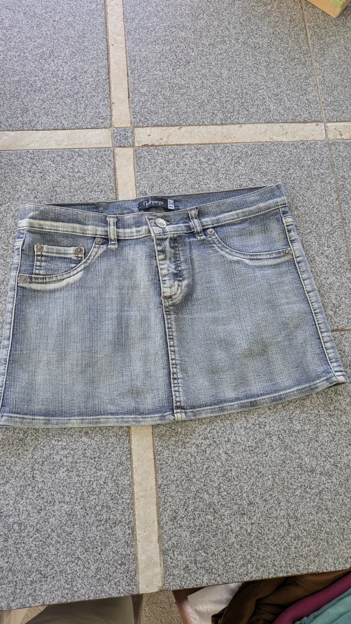 Pollera de jean azul, con bolsillos delanteros y traseros. Cierre y botón en la parte frontal.