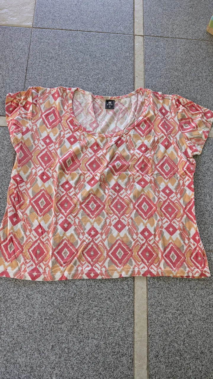 Remera estampada con rombos en tonos rosas, naranjas y beige. Escote redondo y mangas cortas.
