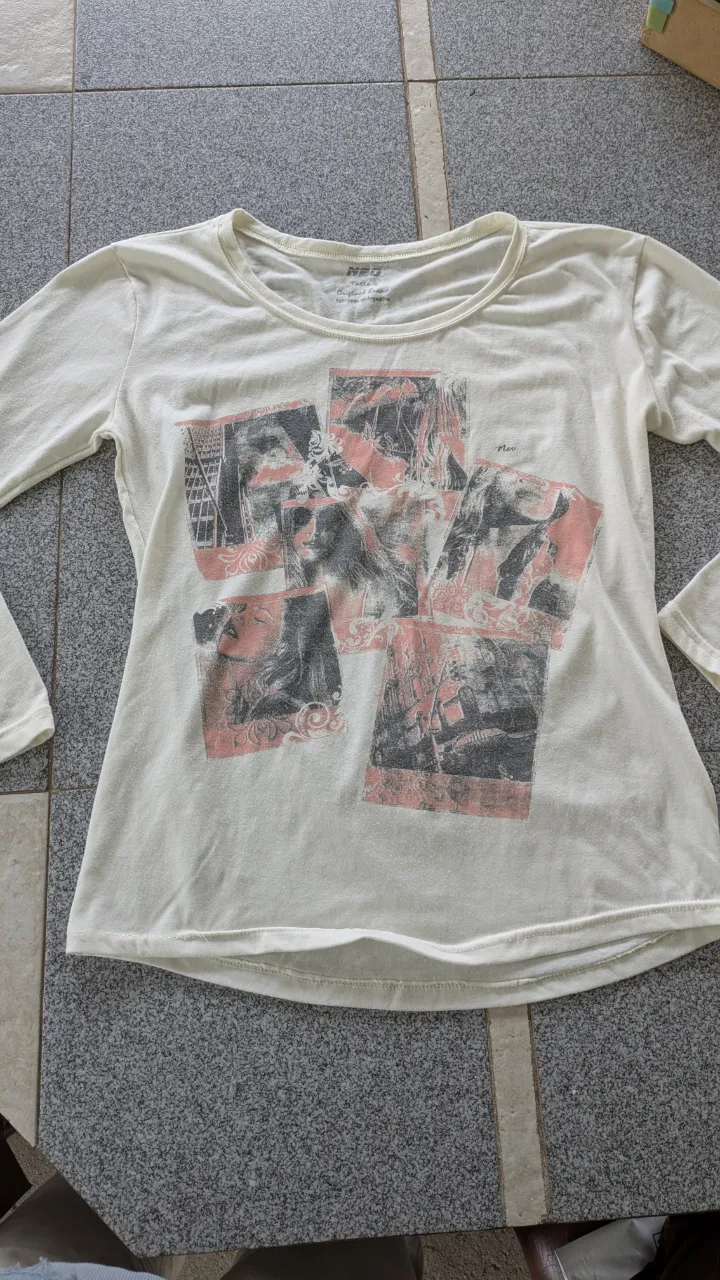Remera blanca de manga larga con estampa de fotos en tonos grises y rosas. Cuello redondo.