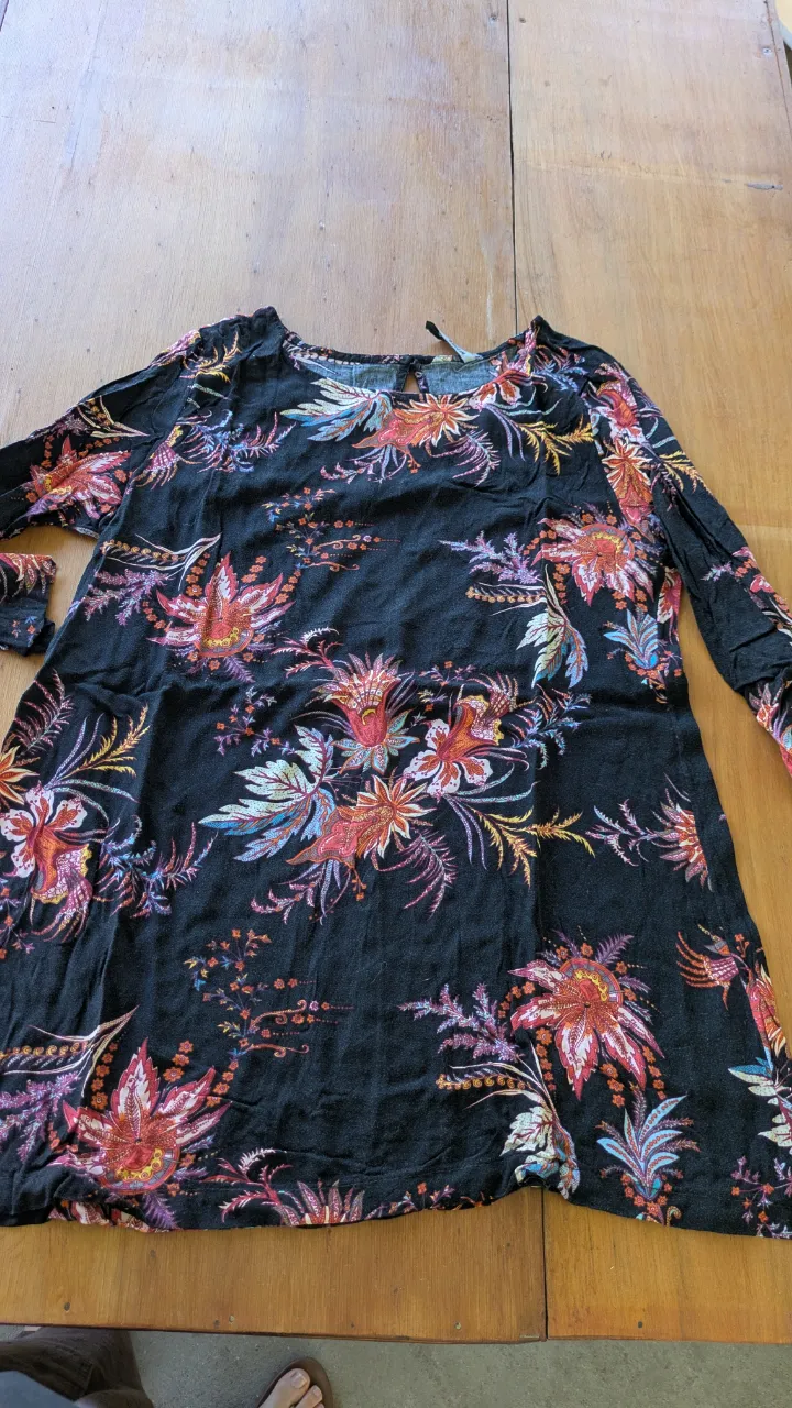 Remeron vestido estampado con flores en tonos vibrantes sobre fondo negro. Manga larga y escote redondo. Ideal para un look casual y canchero.