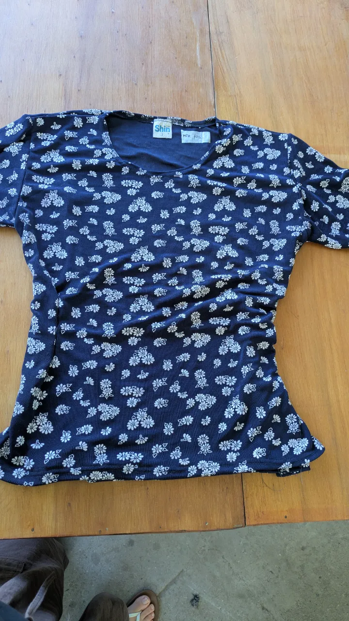 Remera estampada con flores blancas sobre fondo azul marino. Diseño delicado y femenino, ideal para el día a día o una salida casual. Combina con todo y es súper cómoda. estrecha.