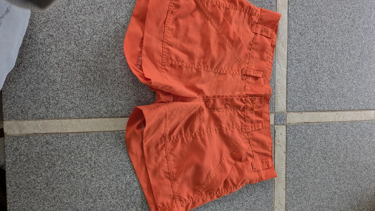 Shorts de gabardina color naranja. Tienen bolsillos delanteros y traseros.