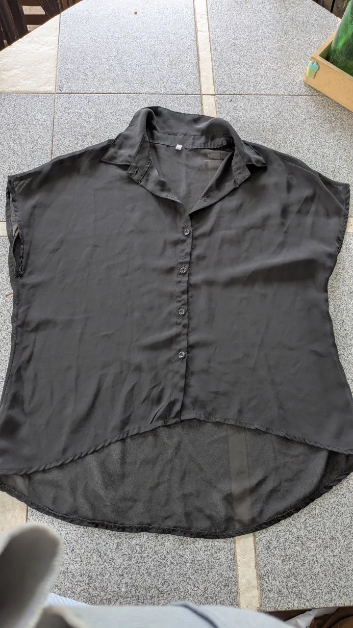 Camisa negra de botones al frente y cuello camisero. Manga corta.