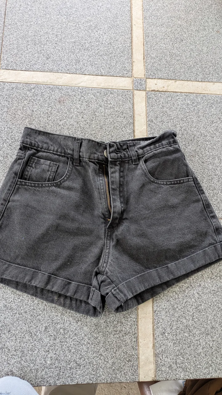 Shorts de jean color gris oscuro con cierre y dos bolsillos delanteros. Tiene dos bolsillos traseros.