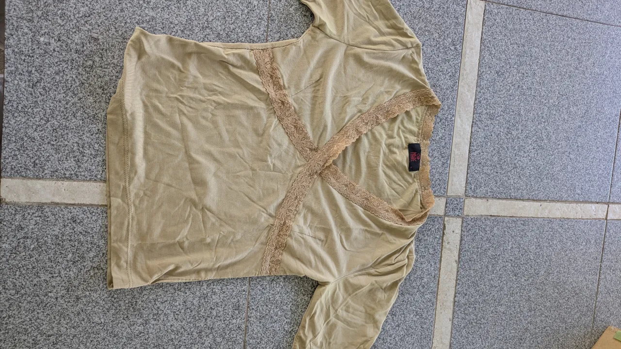 Remera manga larga color beige con detalles de encaje en el escote y puños. Posee una etiqueta interior con el logo de la marca.