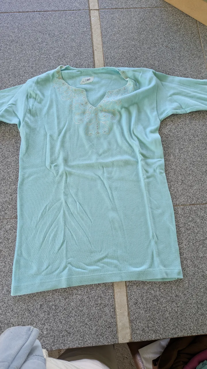 Remera manga corta color celeste con cuello en V y bordados plateados en la zona del escote.