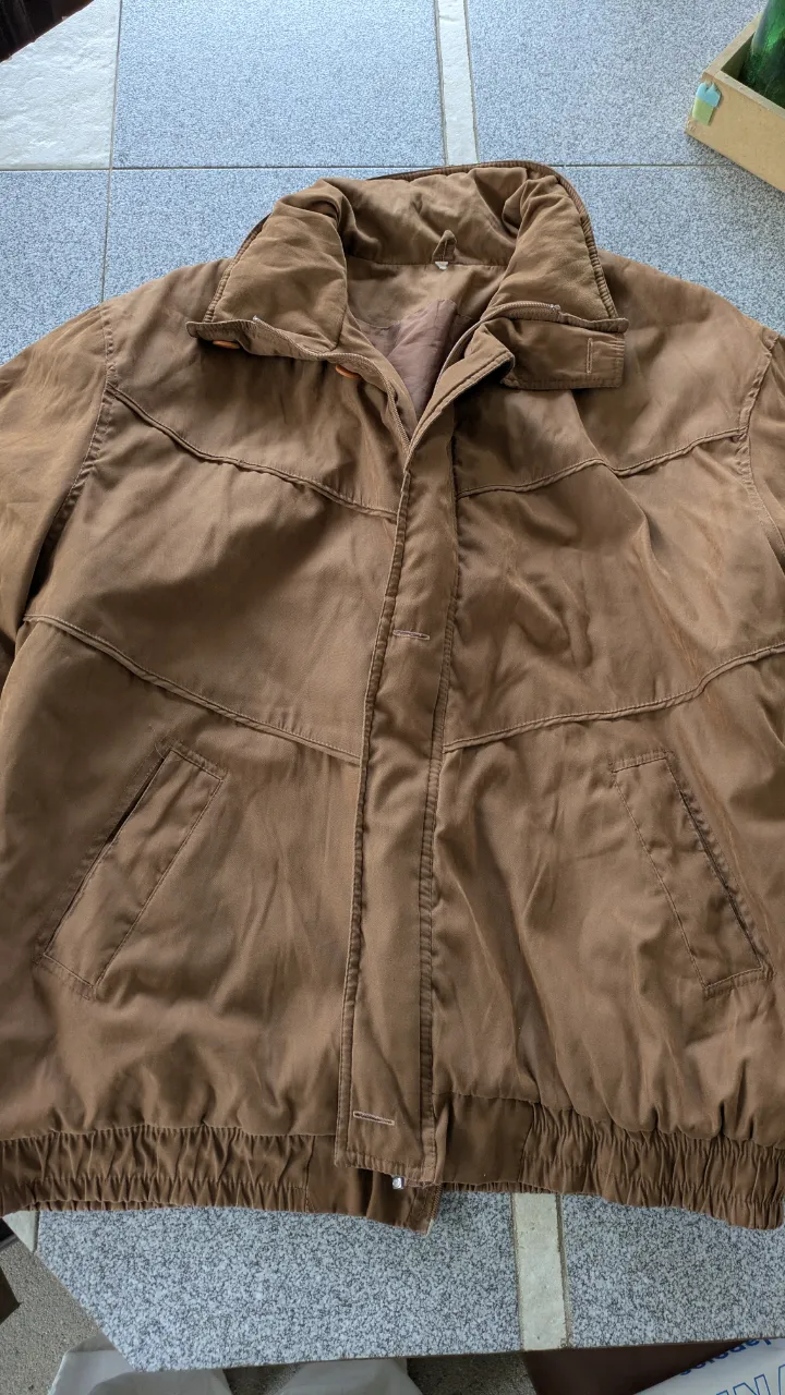 Campera marrón con cuello alto y cierre. Posee bolsillos frontales con solapa y puños elastizados. Interior forrado con bolsillo.