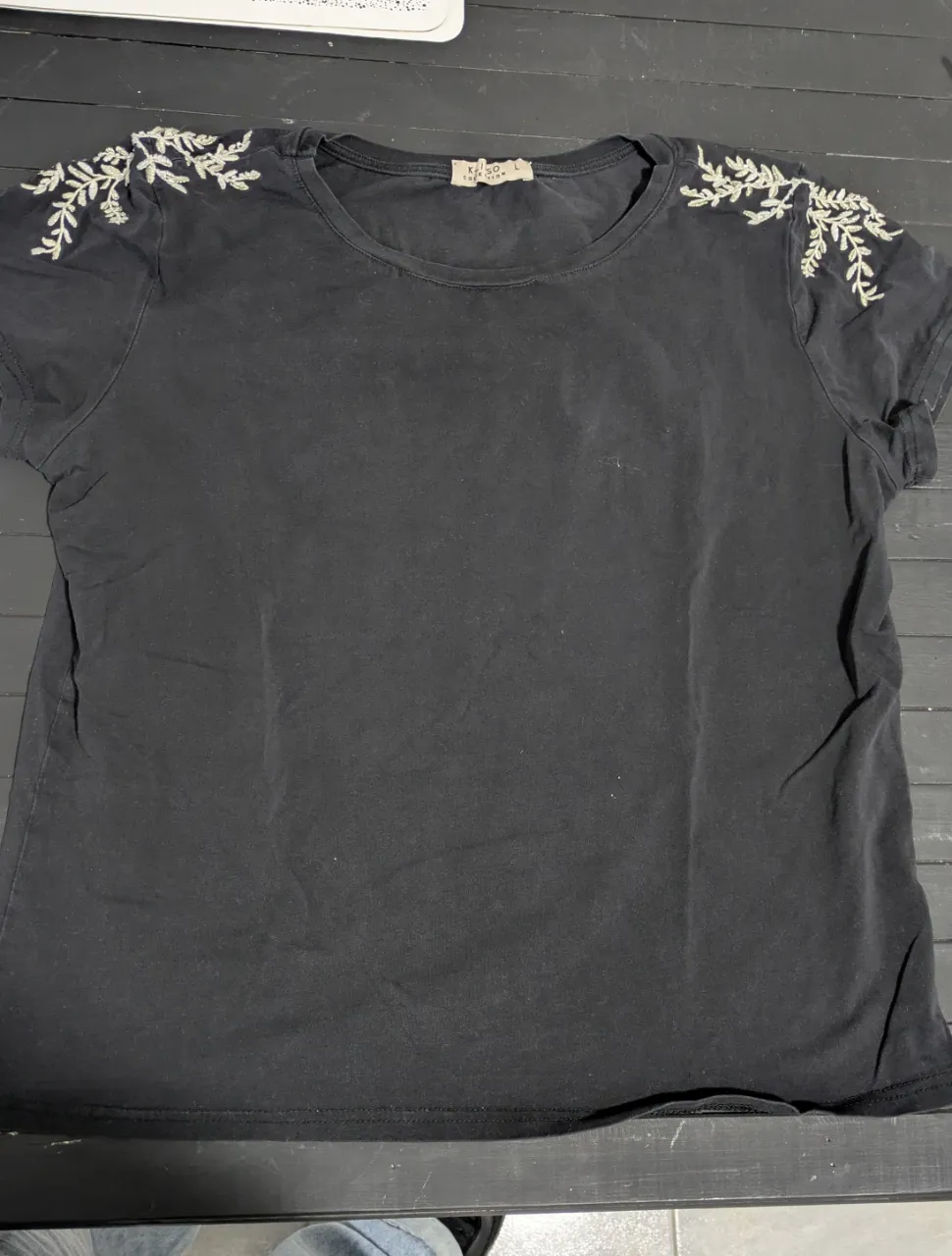 Remera negra de manga corta con bordado de hojas en los hombros. M o L