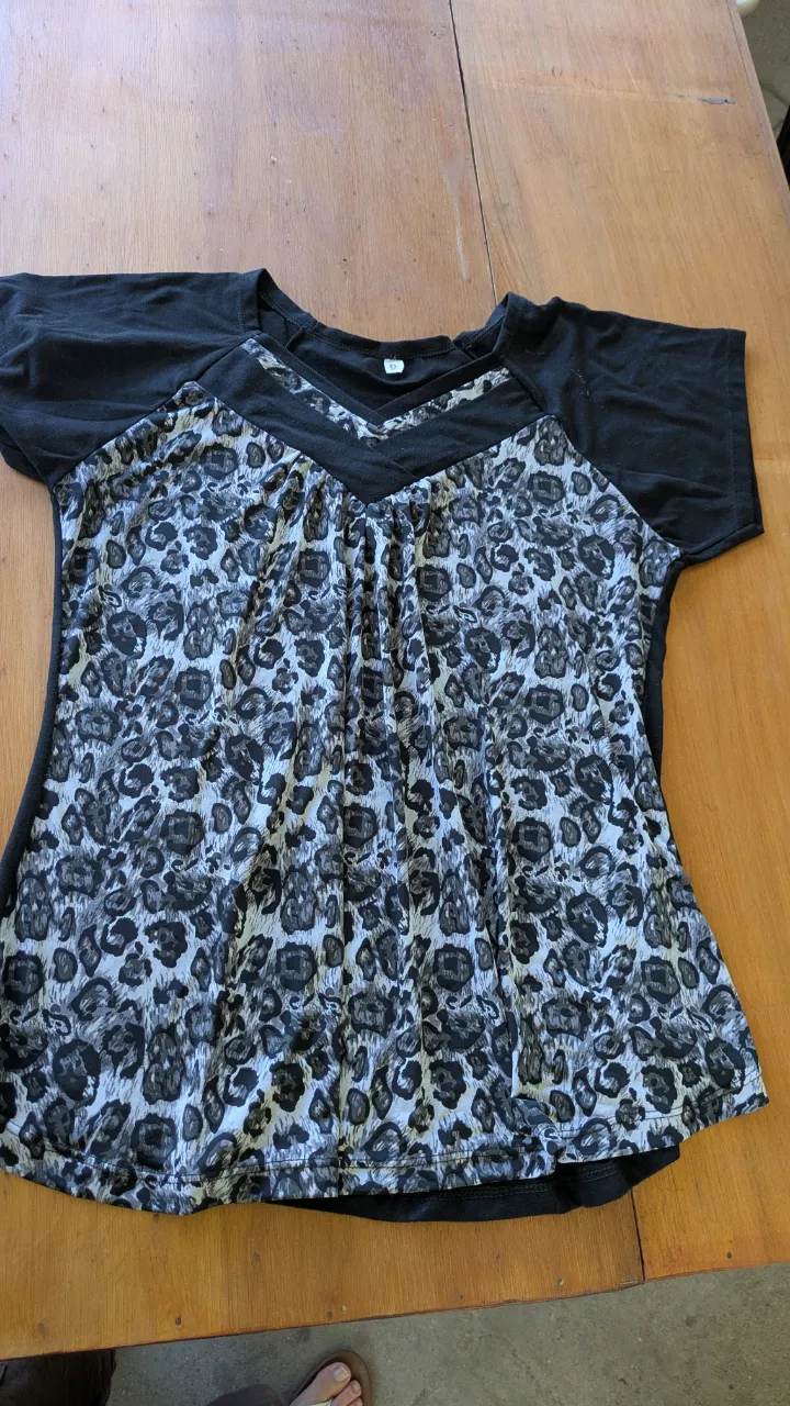 Remera manga corta con estampa animal print en blanco y negro. El torso tiene un diseño con frunces y un escote en V cruzado. Las mangas son lisas y negras. talle 6.