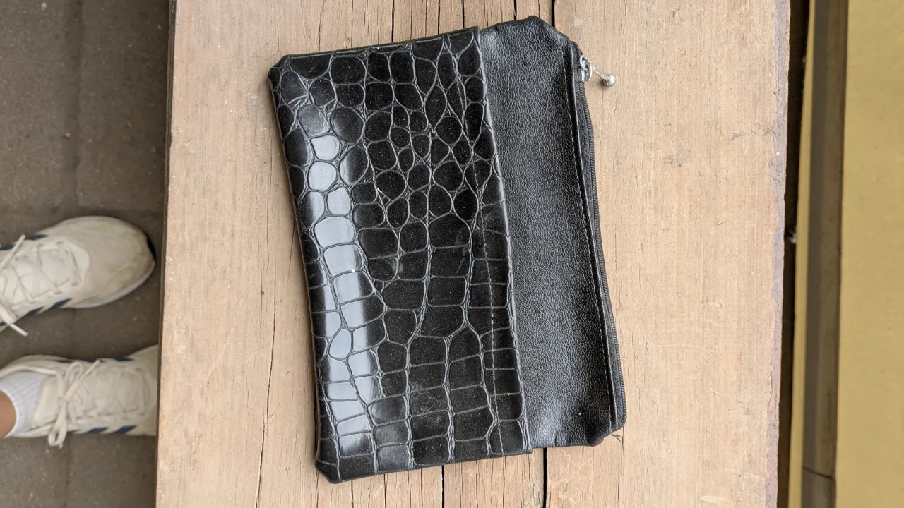 Billetera negra con textura de cocodrilo y cierre.