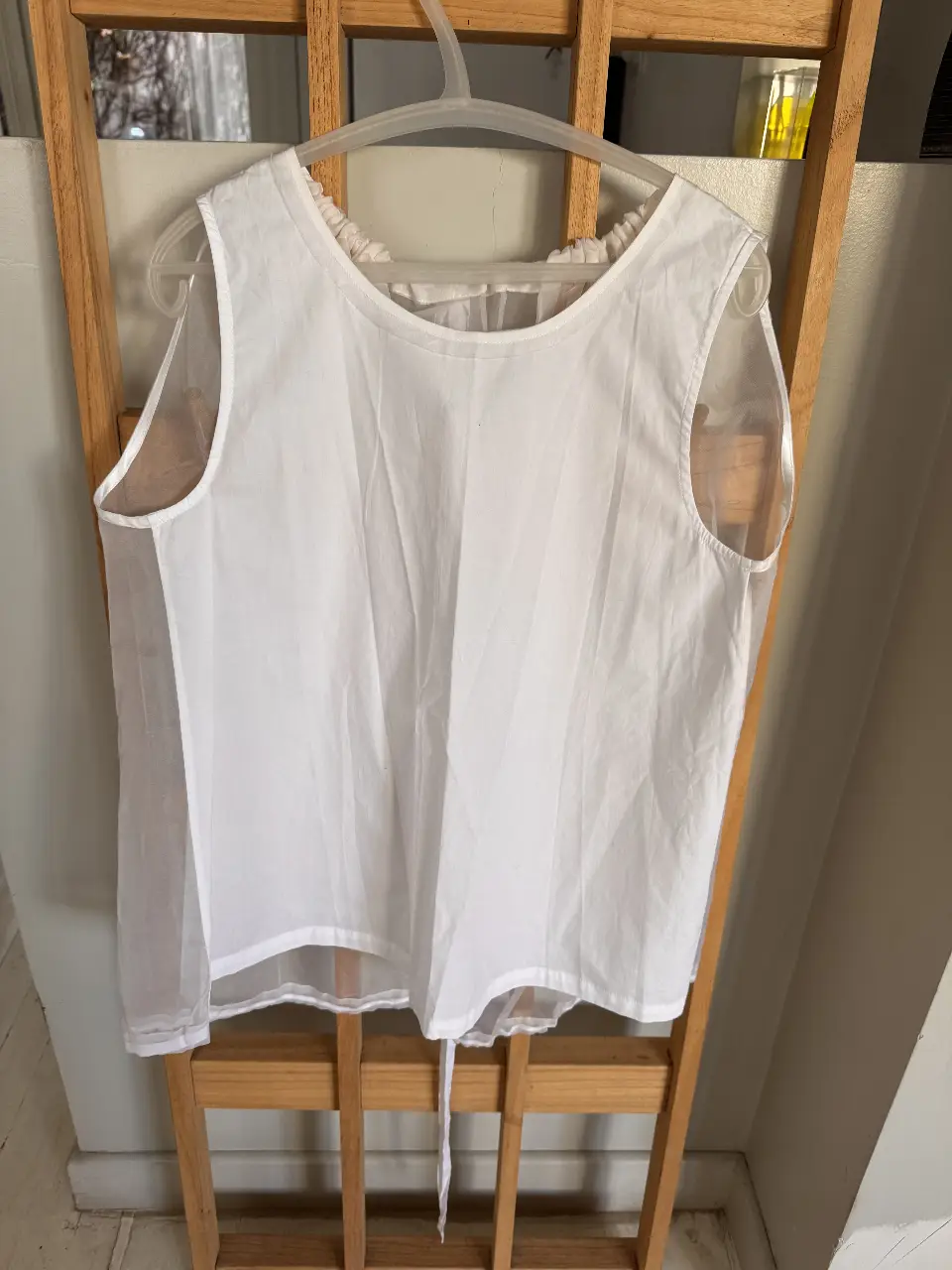 Blusa blanca con detalles de tul en los laterales y en la parte superior, ideal para un look fresco y elegante.