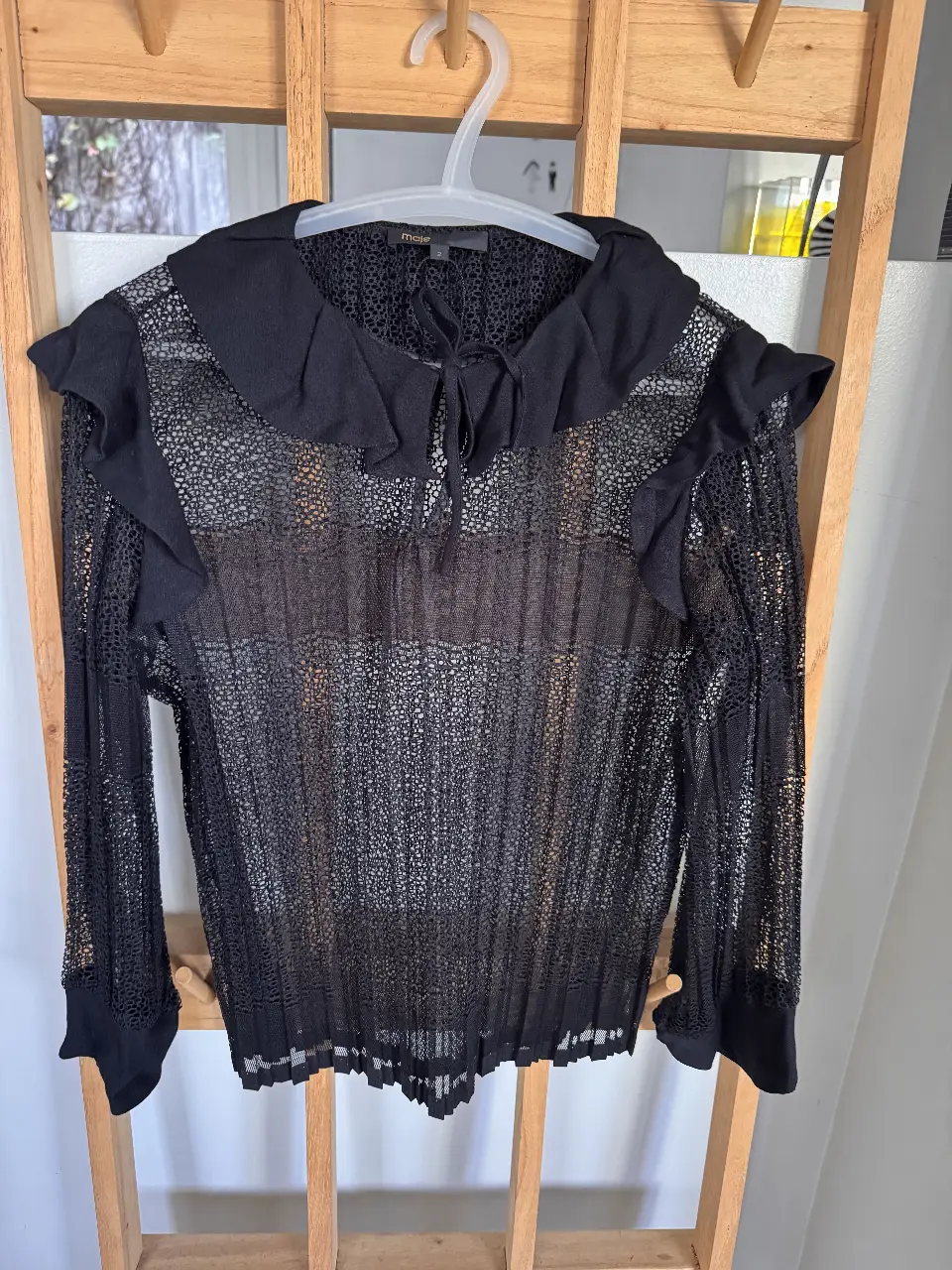 Blusa de encaje negro de la marca Maje, con cuello con volados y mangas largas. Talle 2.