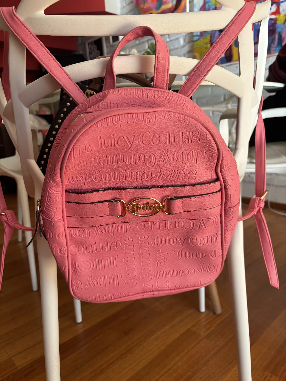 Mochila Juicy Couture rosa, con el logo de la marca en relieve y detalles dorados. Ideal para un look casual y femenino.
