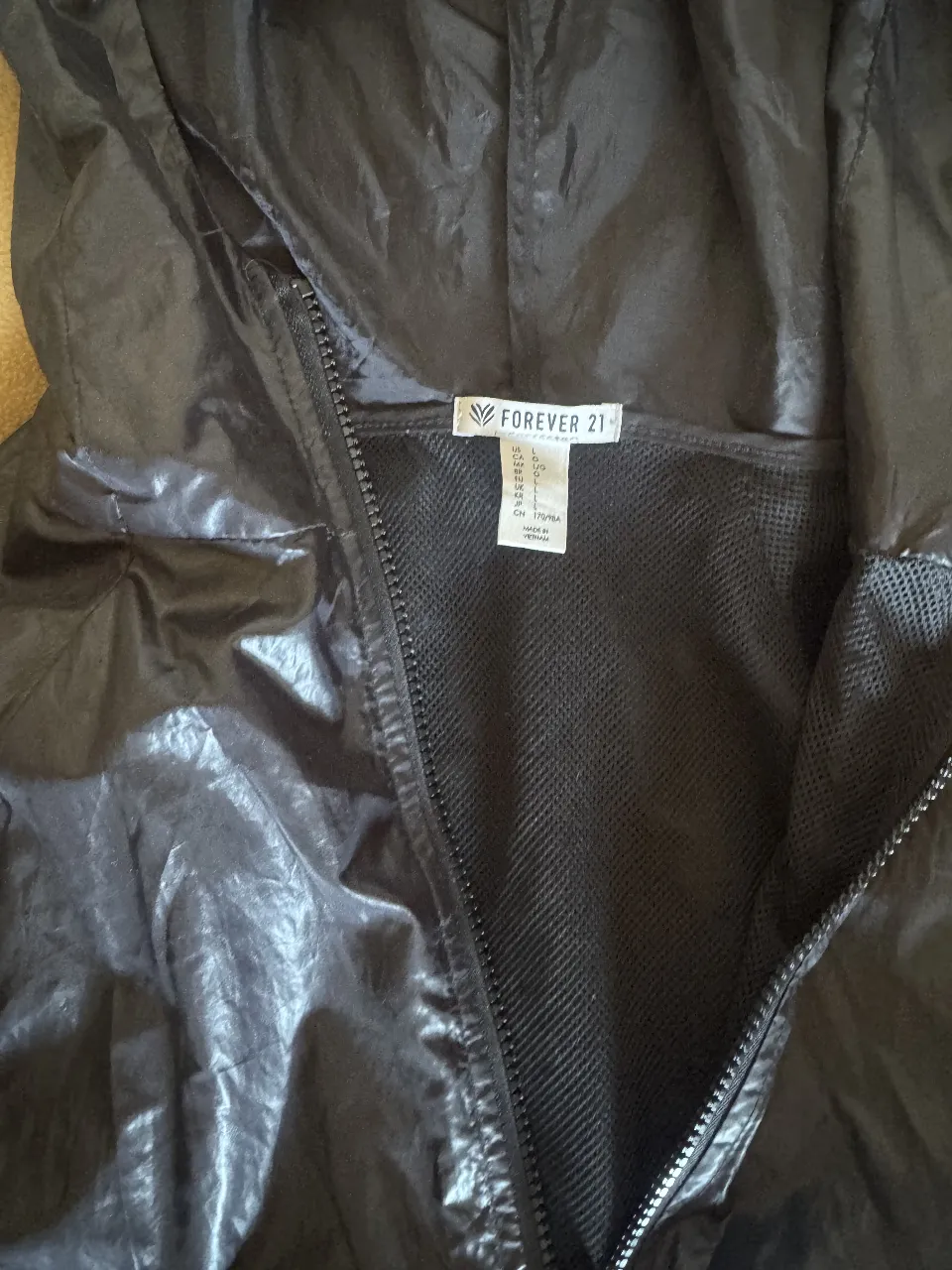 Campera deportiva negra con capucha, cierre frontal y detalles de malla. Ideal para actividades al aire libre o para un look casual y cómodo.