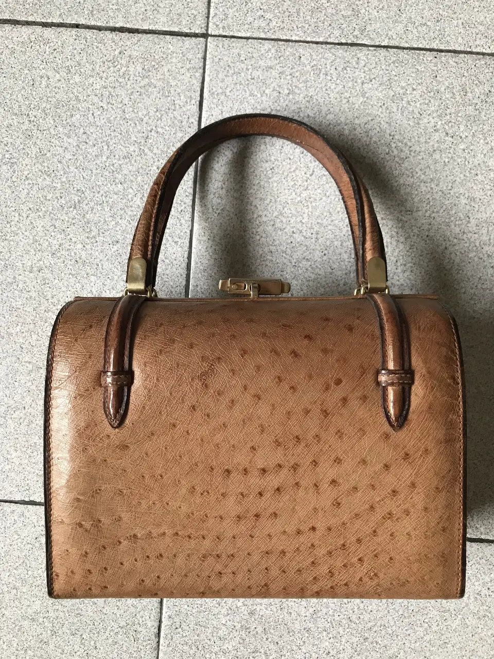 Cartera vintage de mano, con textura de cuero y detalles dorados. Ideal para un look elegante y sofisticado.