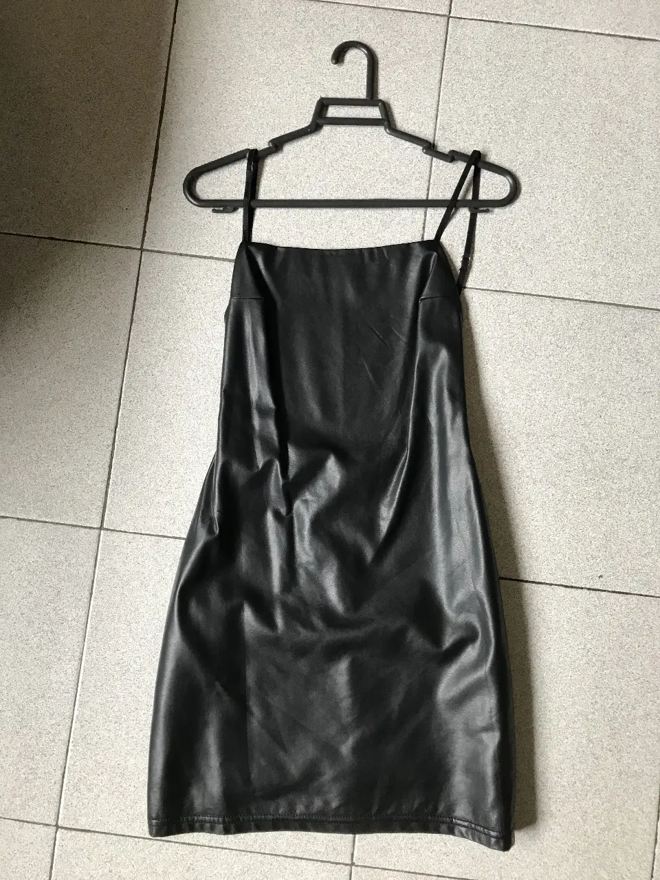 Vestido mini negro de cuero sintético con tiras finas ajustables. Ideal para una salida nocturna o evento especial. Diseño liso y elegante.