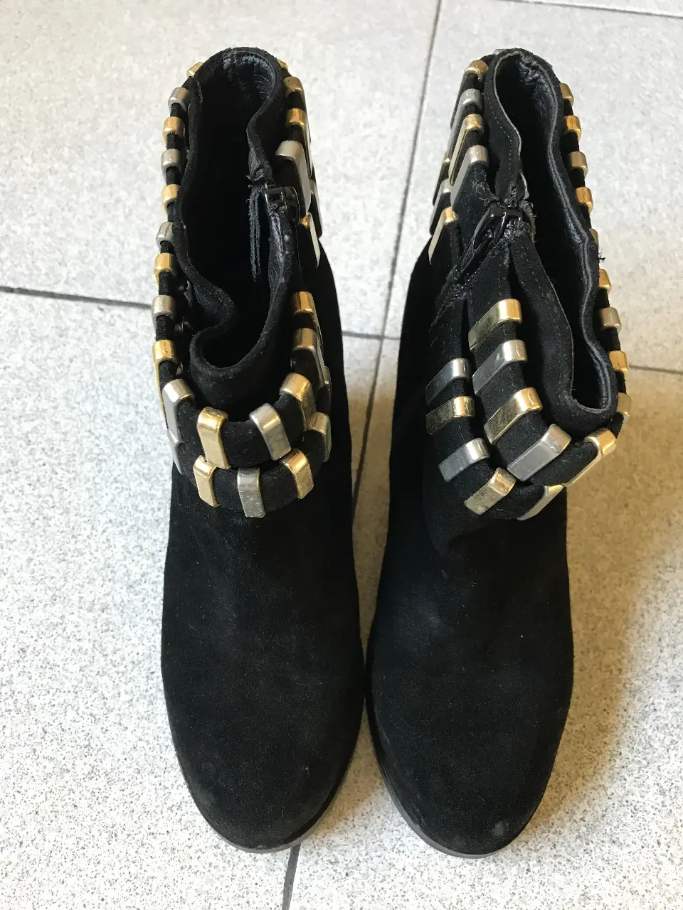 Botines negros de gamuza con detalles dorados y plateados en el borde superior. Diseño elegante y moderno, ideales para complementar cualquier look.
