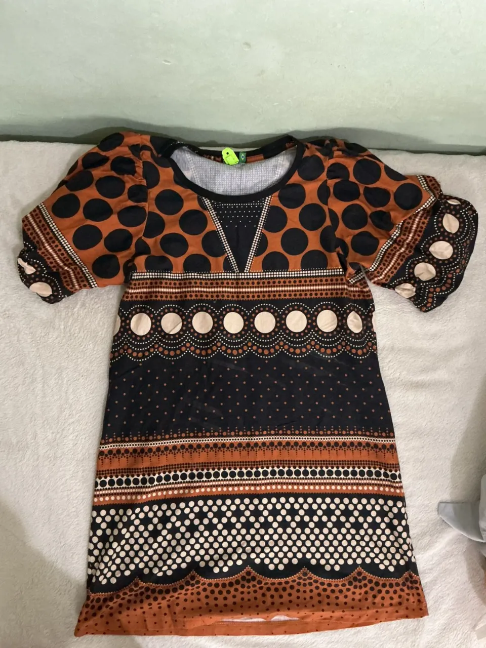 Vestido corto estampado con lunares y detalles geométricos. Posee mangas cortas abullonadas y un escote en V. Ideal para un look casual y divertido.