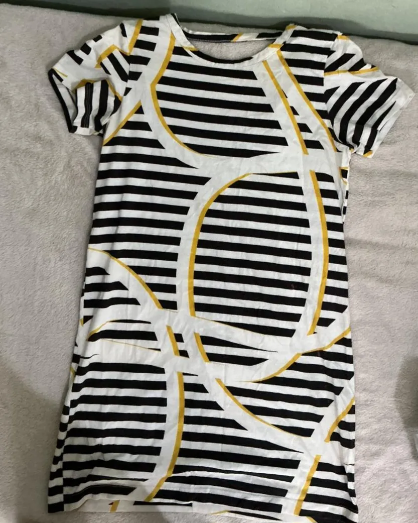 Vestido corto de manga corta con un diseño moderno de rayas horizontales blancas y negras, realzado por un patrón abstracto en tonos amarillos y blancos. Ideal para un look casual y canchero.