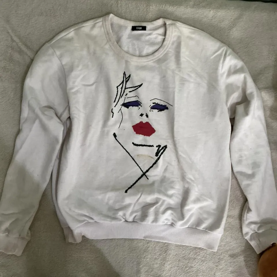 Buzo blanco con estampa de rostro abstracto en el frente. Diseño moderno y original, ideal para un look casual y con onda.