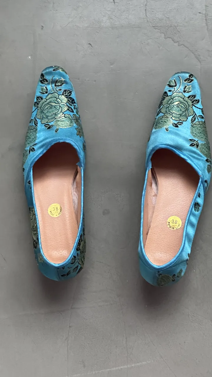 Elegantes zapatos de mujer, estilo slipper, de Jacqard color turquesa con bordados florales en verde y detalles dorados. Ideales para eventos especiales o para darle un toque sofisticado a tu look diario. Talle 38.
