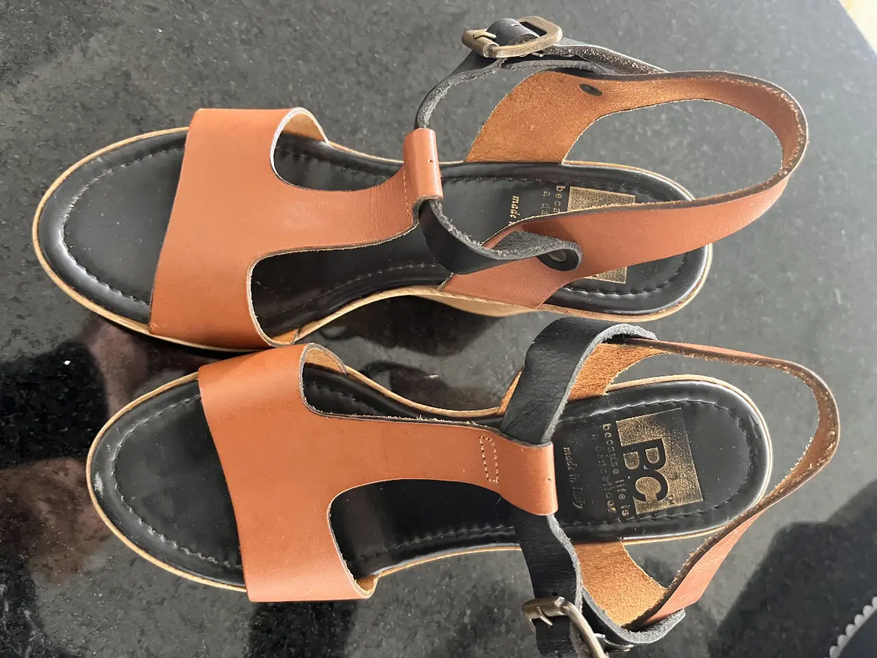 Sandalias de cuero con plataforma de madera y detalles en negro. Ideales para un look casual y cómodo.