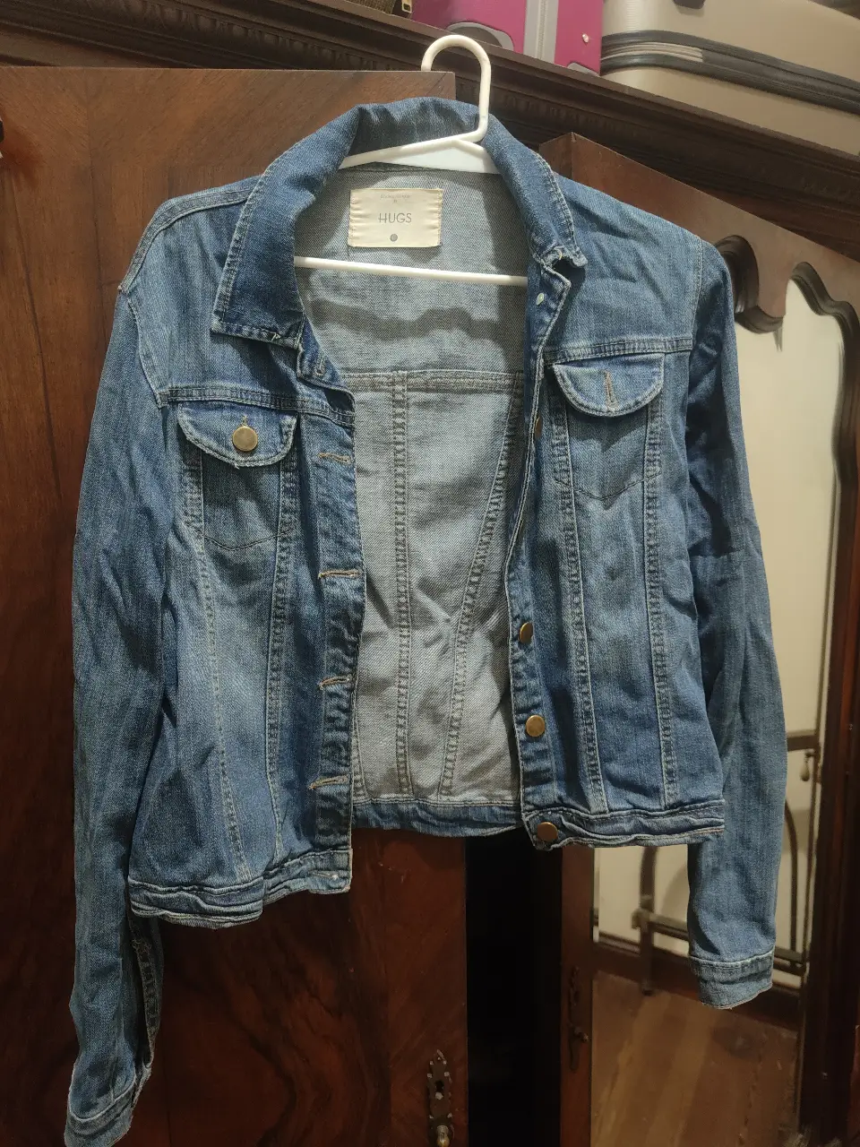 Campera de jean azul, con botones dorados y bolsillos delanteros. Marca HUGS. Ideal para un look casual y versátil.
