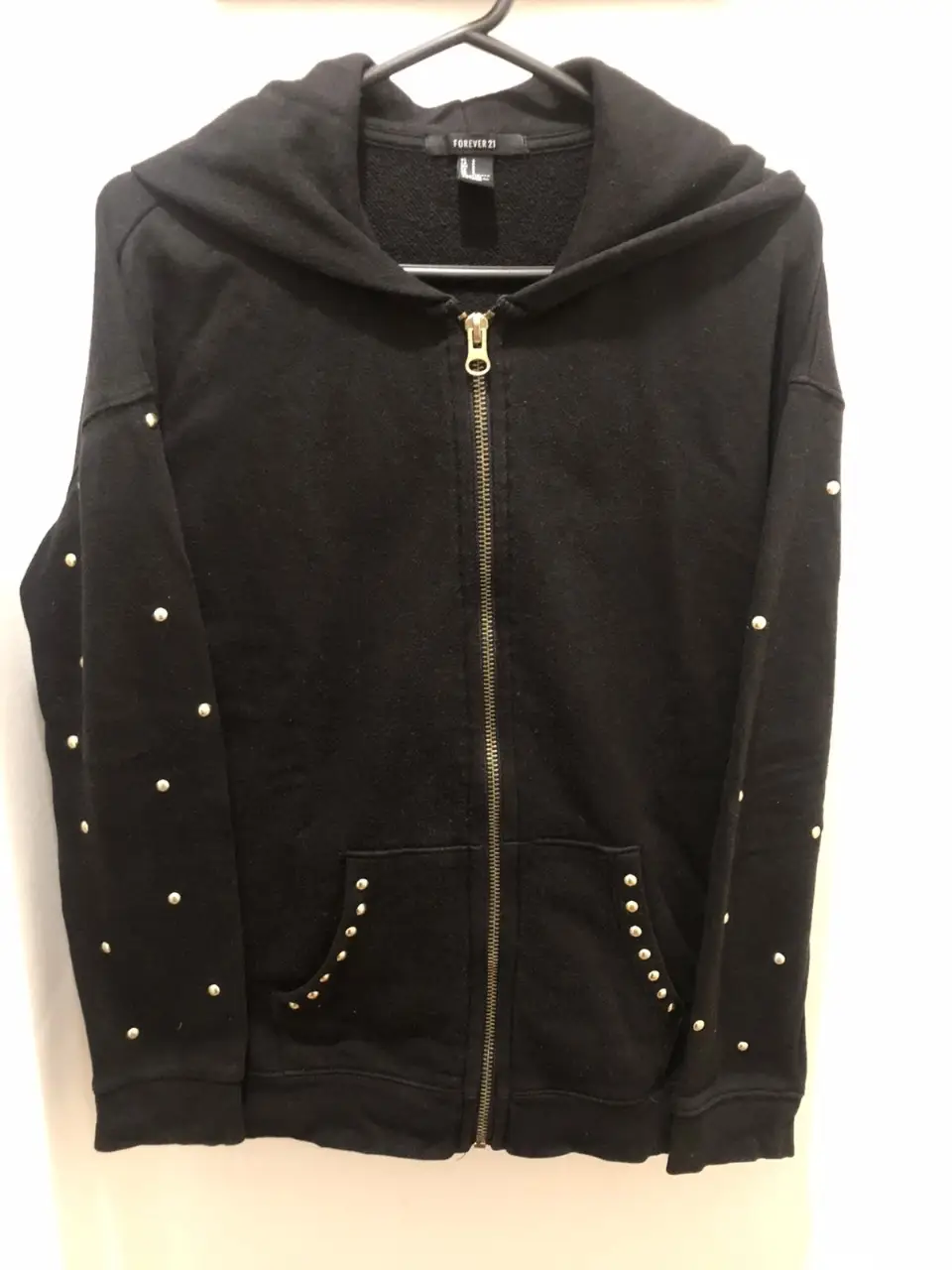 Buzo negro de Forever 21 con cierre y detalles de tachas doradas. Ideal para un look casual y canchero.