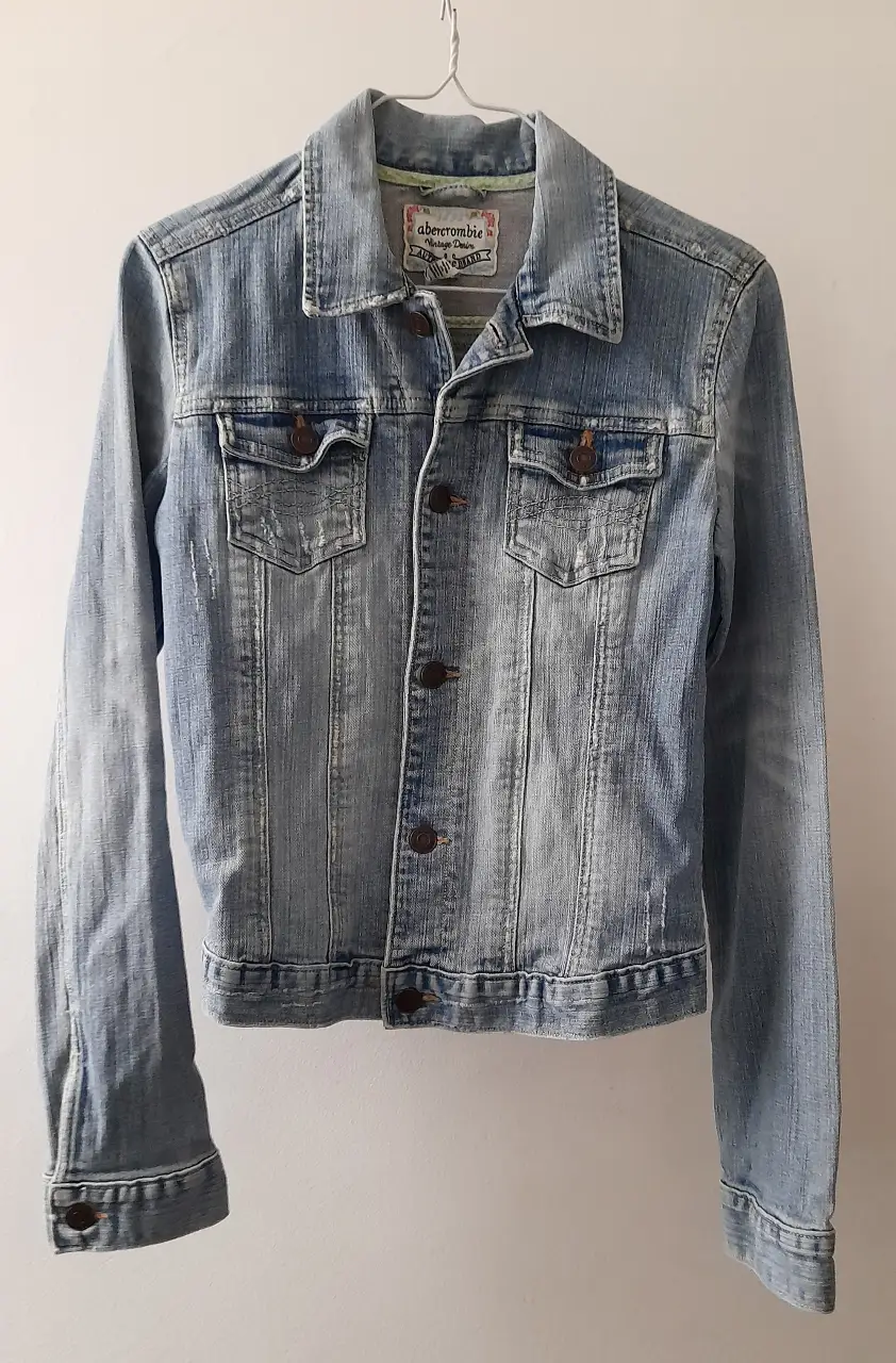 Campera de jean Abercrombie & Fitch vintage, ideal para un look casual y relajado. Confeccionada en denim de alta calidad, esta campera presenta un diseño clásico con dos bolsillos delanteros y cierre con botones. Perfecta para combinar con cualquier outfit.