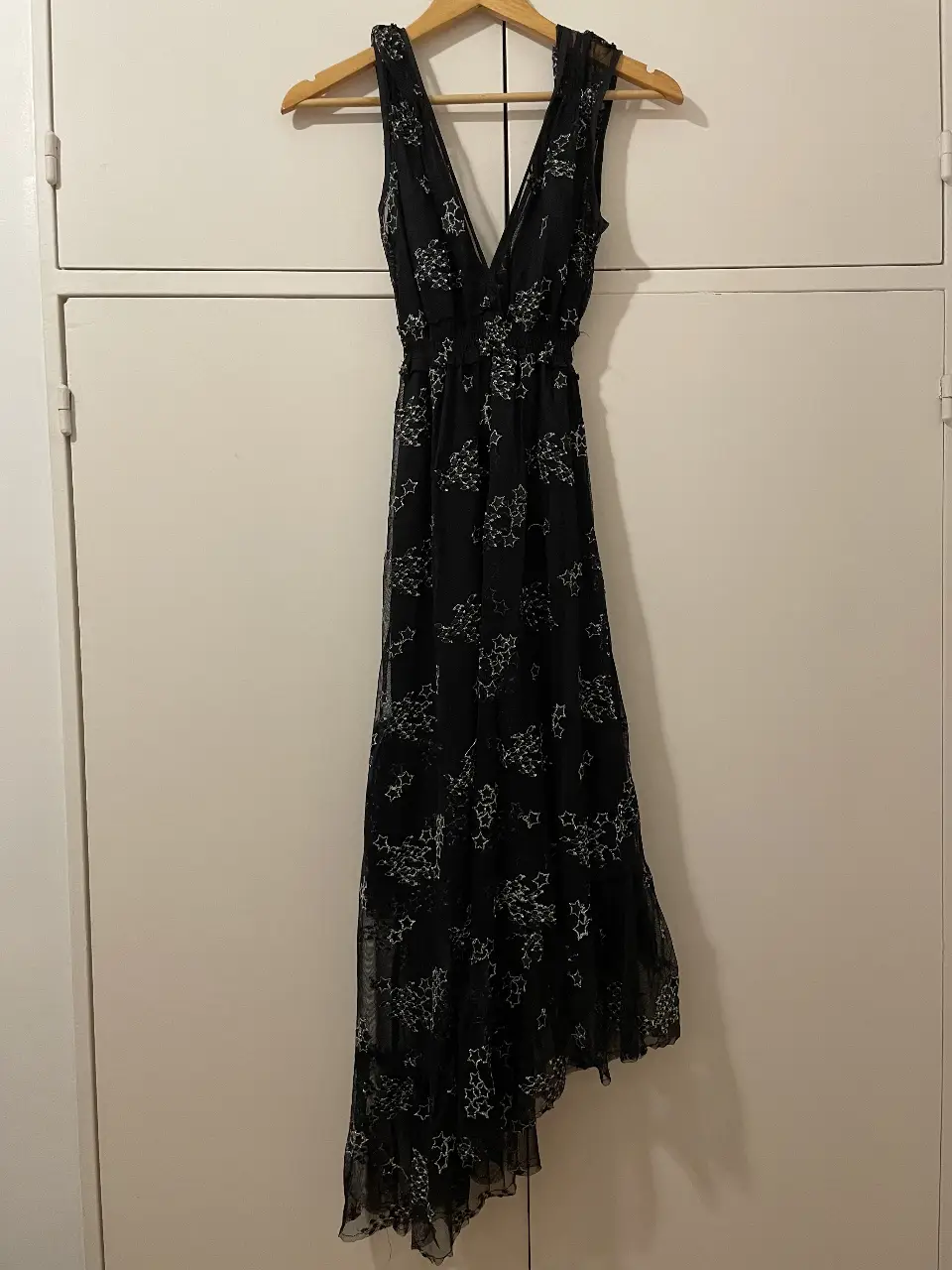 Vestido largo asimétrico, de fiesta, color negro con estampado de estrellas blancas. Diseño con escote en V y detalle fruncido en la cintura. Viene con una base negra lisa para usar debajo. Ideal para eventos especiales. 