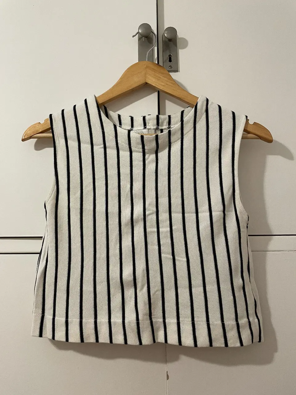 Top sin mangas a rayas verticales en blanco y negro. Ideal para un look casual y fresco. Con nuditos en la espalda. Marca Zara.