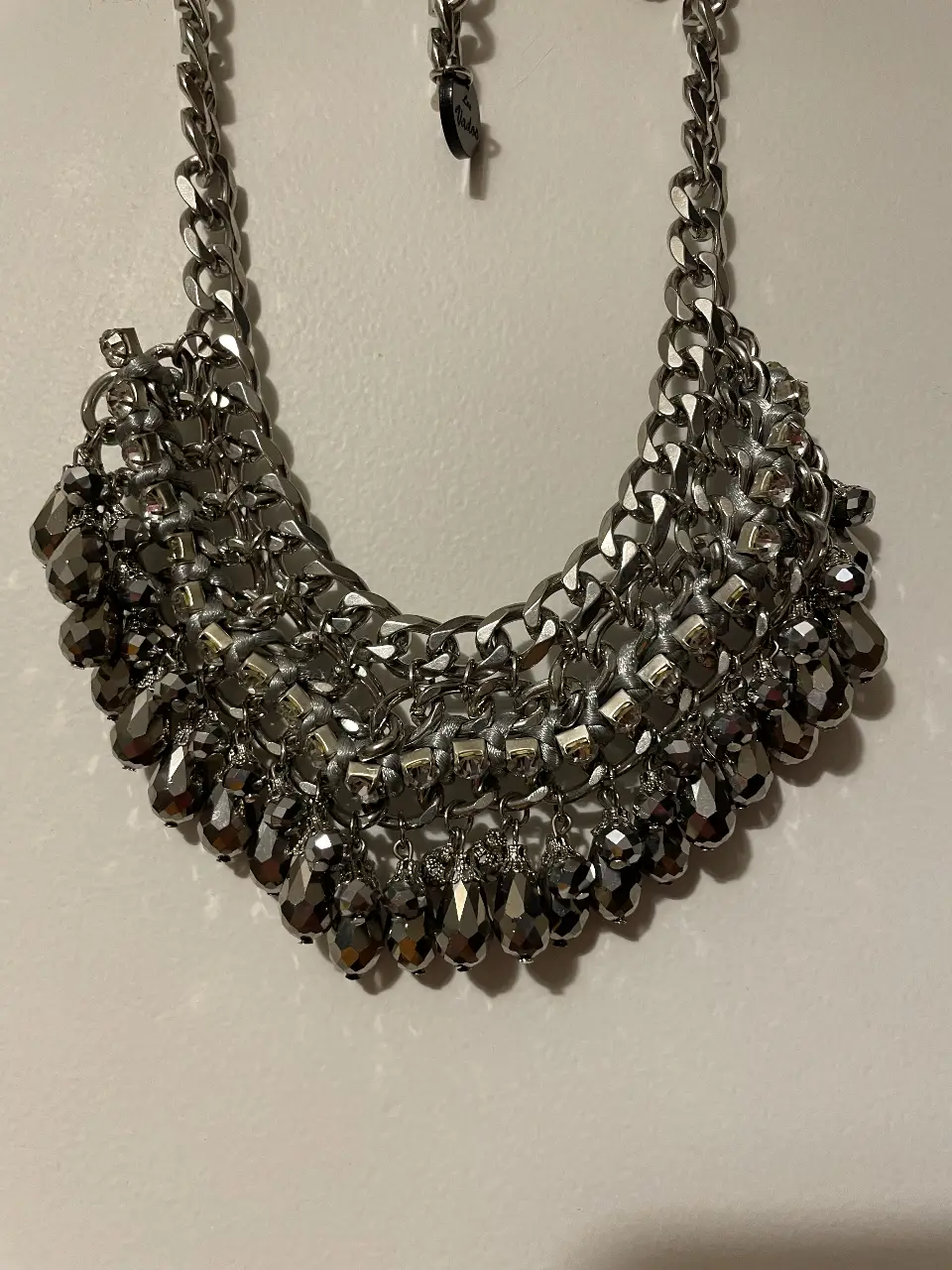 Collar plateado con detalles de cadenas y piedras facetadas. Ideal para darle un toque elegante a cualquier look de fiesta.