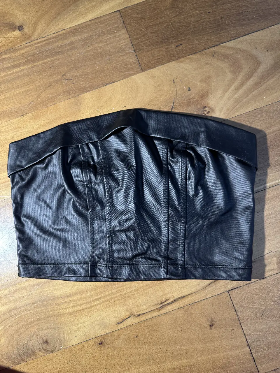 Top negro de cuero sintético, ideal para un look audaz y moderno. Perfecto para salir o para eventos especiales. Un básico que no puede faltar en tu guardarropa.