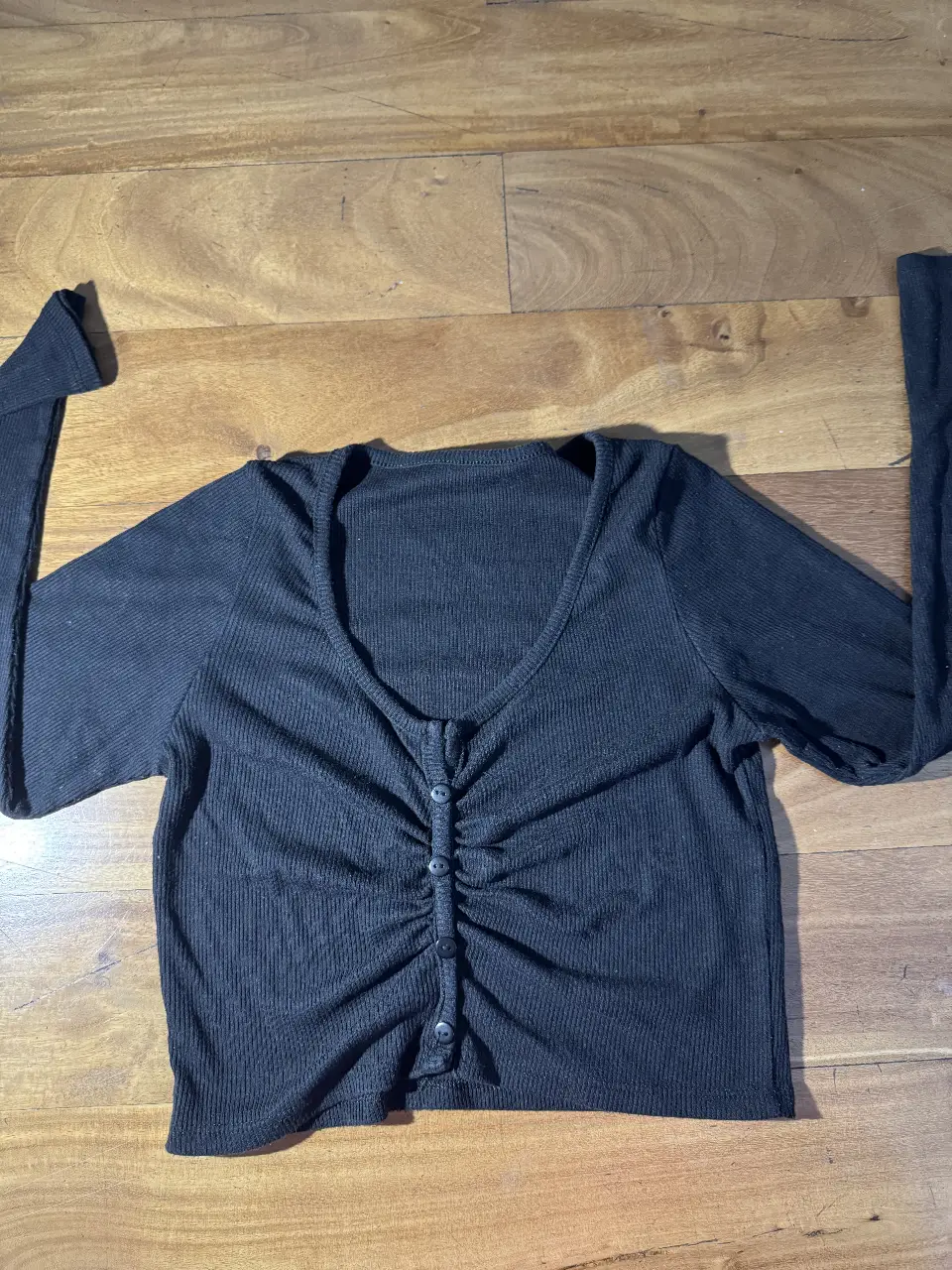 Top negro de manga larga con botones en el frente. Ideal para un look casual y moderno.