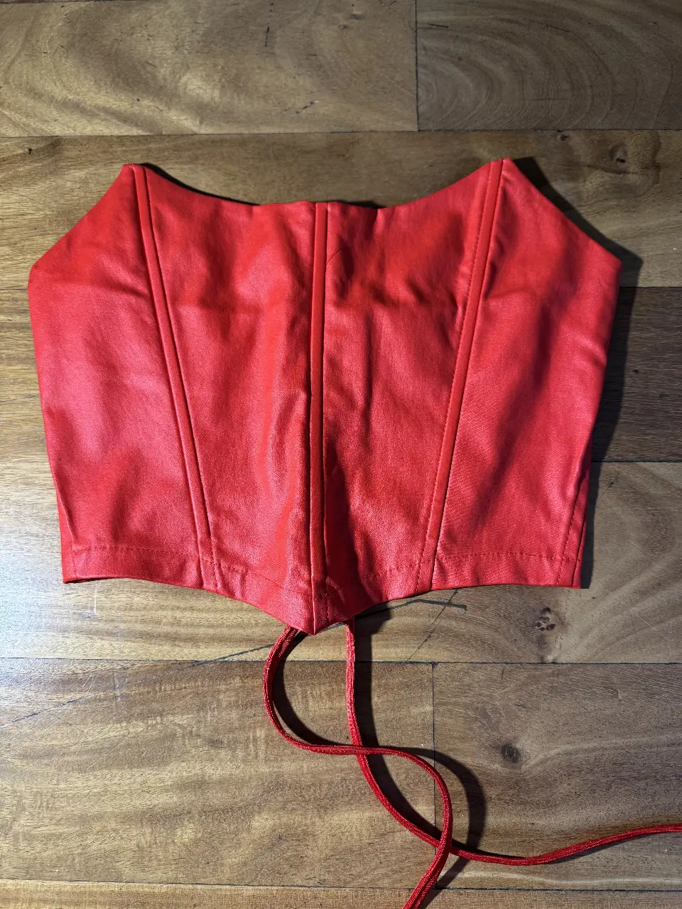 Top corset de cuero sintético rojo, con ajuste de cordones en la espalda. Ideal para looks de fiesta o disfraces. 